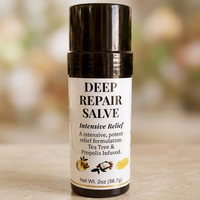 A 2-ounce black twist-up tube of Deep Repair Salve resting on a light-colored surface against a soft, blurred background. The white label features bold black text reading "DEEP REPAIR SALVE," with subtext that says "Intensive Relief," "A intensive, potent relief formulation," and "Tea Tree & Propolis Infused," accompanied by small graphics of botanical ingredients near the bottom.