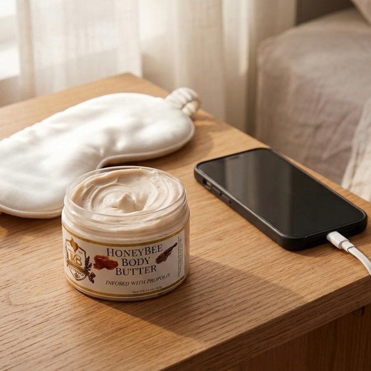 A product photograph featuring three open jars of Texas Bee body butter lined up on a white marble slab resting on a rustic wooden board. From left to right: Gentle Grove Body Butter with a pale green cream, styled with fresh sage leaves and a piece of propolis; Lavender Body Butter with a light purple cream, accompanied by sprigs of dried lavender; and Honeybee Body Butter with a soft peach cream, set next to a clear glass honey dipper and raw honeycomb. Each jar features a white label with gold trim and t