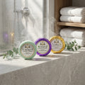 Three Texas Bee shower steamers arranged on a stone ledge. An unwrapped green steamer labeled 